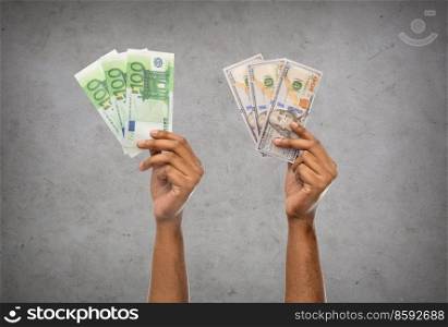 finance, currency and people concept - close up of male hands holding dollar and euro money over grey stone background. close up of hands holding money over grey