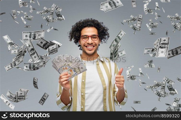 finance, currency and people concept - happy man holding hundreds of dollar money banknotes showing thumbs up over grey background. happy man with dollar money showing thumbs up