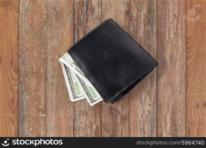 finance, investment, saving and cash concept - close up of dollar money in wallet on wooden table