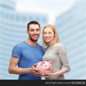 finance, money and family concept - smiling couple holding big piggy bank