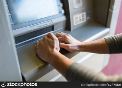 finance, money, bank and people concept - close up of hand entering pin code at atm machine