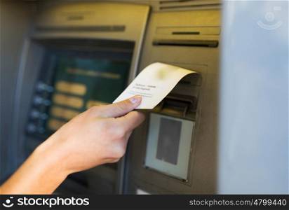 finance, money, bank and people concept - close up of hand taking receipt from atm machine