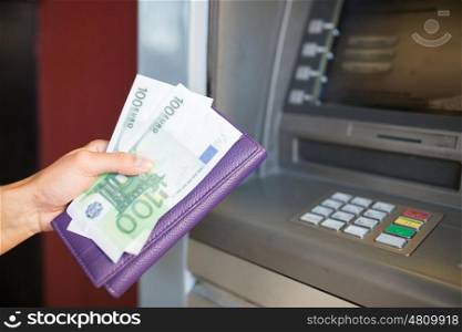 finance, money, bank and people concept - close up of hand with wallet withdrawing cash at atm machine