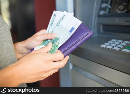 finance, money, bank and people concept - close up of hand with wallet withdrawing cash at atm machine