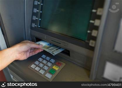 finance, money, bank and people concept - close up of hand withdrawing cash at atm machine