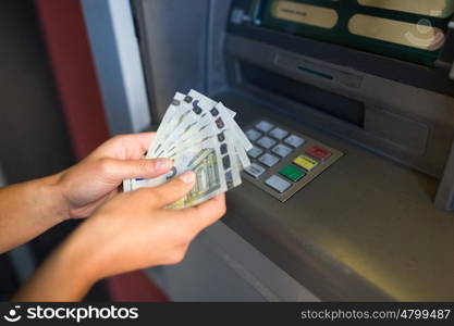 finance, money, bank and people concept - close up of hand withdrawing cash at atm machine