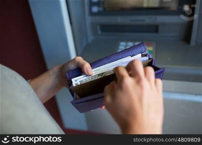 finance, money, bank and people concept - close up of hands with cash in wallet at atm machine