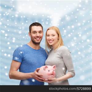 finance, money, people and family concept - smiling couple holding big piggy bank over snowy city center background