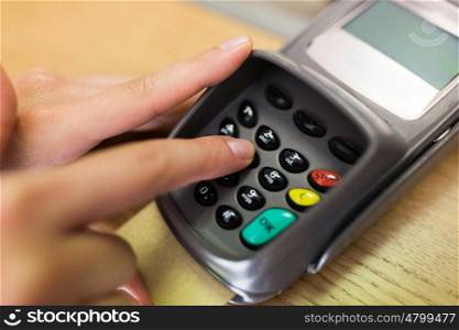 finance, money, technology, payment and people concept - close up of hand entering pin code to card reader terminal