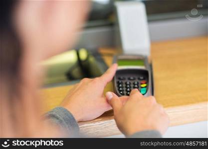 finance, money, technology, payment and people concept - close up of hand entering pin code to card reader terminal