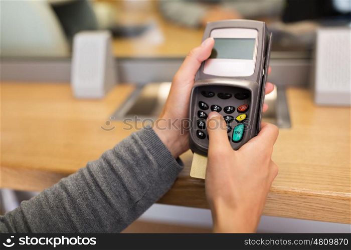 finance, money, technology, payment and people concept - hand entering pin code to card reader terminal