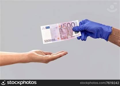 finance, payment and pandemic concept - close up of hand in medical glove giving money away over gray background. close up of hand in medical glove giving money