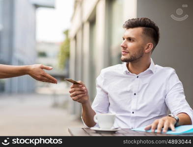 finance, payment, cash free and people concept - young man with credit card paying for coffee at city street cafe