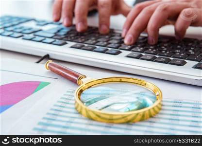 Finance professional working on keyboard with reports. The finance professional working on keyboard with reports