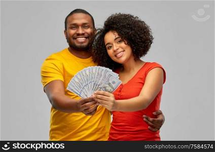 finance, saving and people concept - happy smiling african american couple with dollar money over grey background. happy african american couple with dollar money