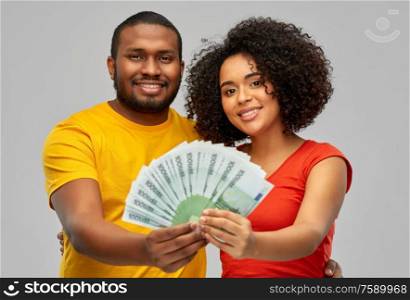 finance, saving and people concept - happy smiling african american couple with euro money over grey background. happy african american couple with euro money