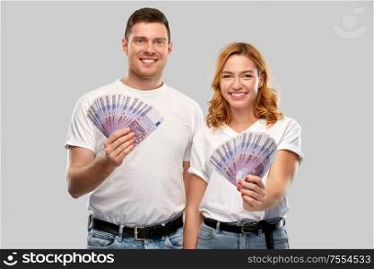 finance, saving and people concept - portrait of happy couple in white t-shirts with euro money over grey background. happy couple in white t-shirts with euro money
