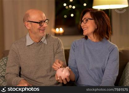finance, savings and people concept - happy senior couple with piggy bank at home. happy senior couple with piggy bank at home