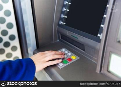 finance, technology, money and people concept - close up of hand entering pin code at cash machine