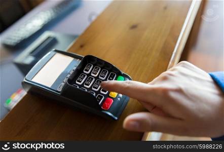 finance, technology, payment and people concept - close up of hand entering pin code to money terminal