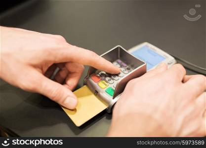 finance, technology, payment , money and people concept - close up of hand entering pin code to bank terminal with credit car
