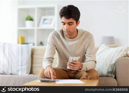 finances, accounting and people concept - man with calculator counting money at home. man with calculator counting money at home