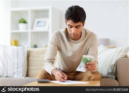 finances, accounting and people concept - man with money and calculator filling papers at home. man with money and calculator filling papers