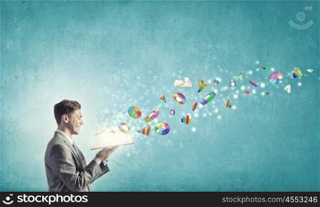 Finances and economics. Young businessman with opened book in hands and icons flying out