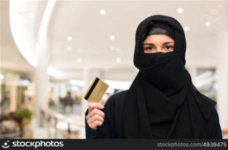 finances and people concept - muslim woman in hijab with credit card over shopping center background. muslim woman in hijab with credit card over white