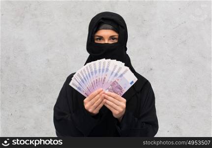 finances and people concept - muslim woman in hijab with money over gray concrete wall background. muslim woman in hijab with money over white