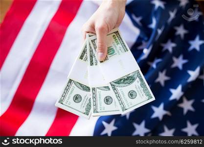 finances, corruption, investment and economics concept - close up of hand with dollar cash money over american flag