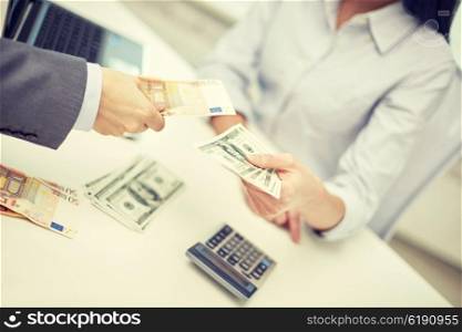 finances, currency, exchange rate, business and people concept - close up of male and female hands giving or exchanging money at office