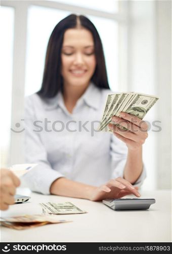 finances, currency, exchange rate, technology and people concept - close up of happy woman counting dollar money with calculator