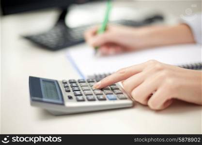 finances, economy, technology and people concept - close up of woman hands with calculator counting and taking notes to notebook