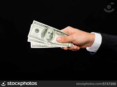 finances, people, savings and poverty concept - close up of male hand holding dollar cash money over black background