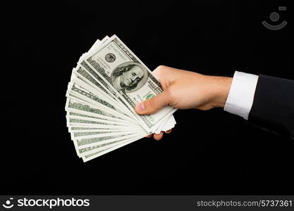 finances, people, savings and wealth concept - close up of male hands holding dollar cash money over black background