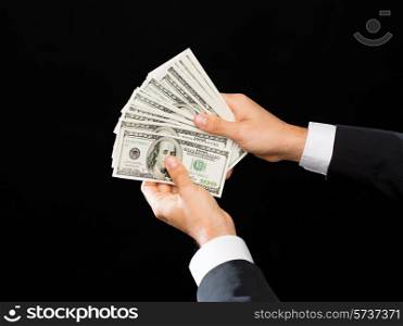 finances, people, savings and wealth concept - close up of male hands holding dollar cash money over black background