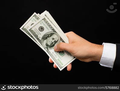 finances, people, savings and wealth concept - close up of male hands holding dollar cash money over black background