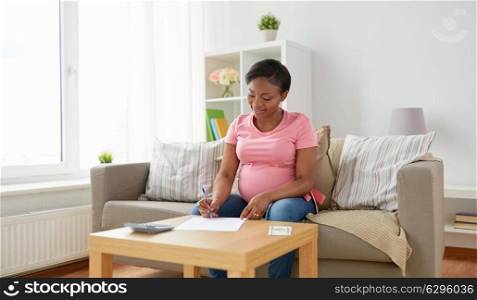 finances, pregnancy and people concept - pregnant african american woman with calculator and money filling papers at home. pregnant woman with bills and money at home