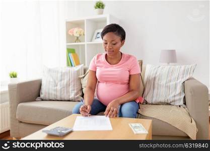 finances, pregnancy and people concept - pregnant african american woman with calculator and money filling papers at home. pregnant woman with bills and money at home