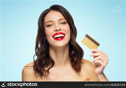 finances, shopping and people concept - happy smiling young woman with red lipstick holding credit card over blue background. beautiful woman with red lipstick and credit card