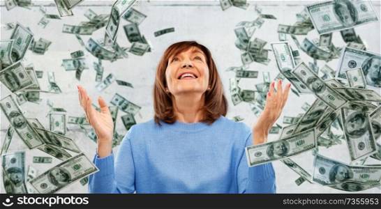 finances, wealth and success concept - grateful senior woman looking up under money falling from above over grey background. grateful senior woman and money falling from above