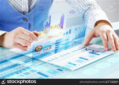 Financial analysis and forecast. Close up of business person investigating infographs with magnifier