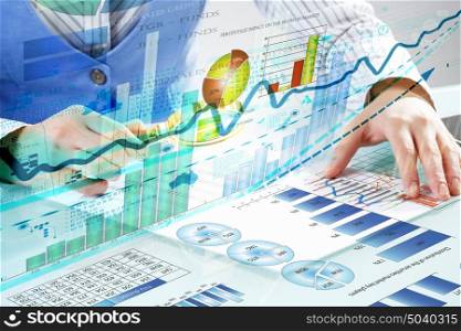 Financial analysis and forecast. Close up of business person investigating infographs with magnifier
