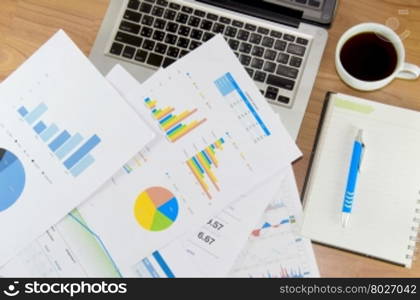 Financial chart on the table with laptop, book and coffee and pen