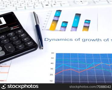 Financial charts and tables on the desktop. Calculator pen. Financial graphs business attributes on the desktop