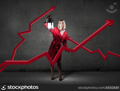 Financial concept with young pretty businesswoman with lantern in darkness. Searching for solution