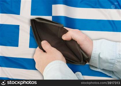 Financial Crisis in Greece - Man&rsquo;s Hand With Empty Wallet and Greek flag