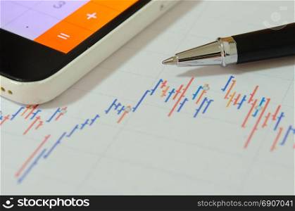 Financial graphs analysis and pen.