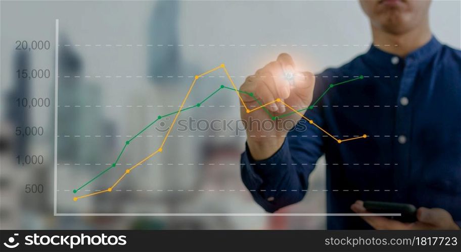 financial graphs and diagrams economic business concepts, investments.hand holding a pen touching digital business graph virtual screen interface.